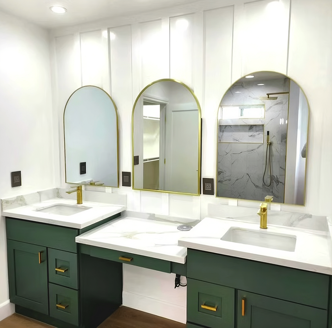 Modern bathroom remodel with green vanities and arched mirrors